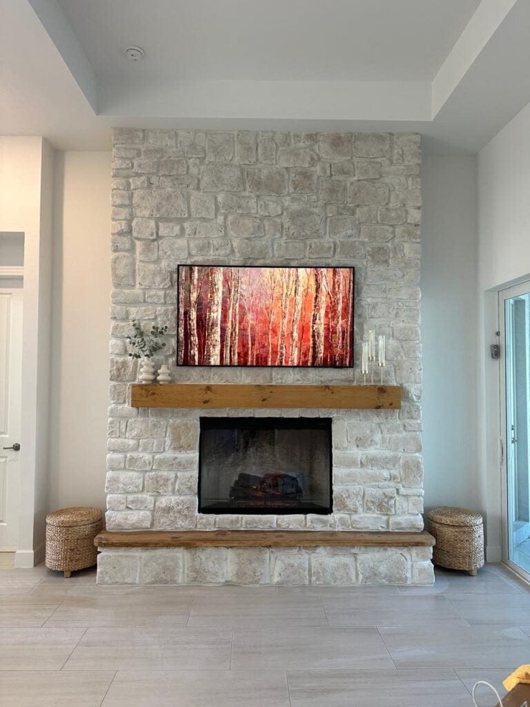 Floor-to-ceiling white stone fireplace wall with rustic wood mantel