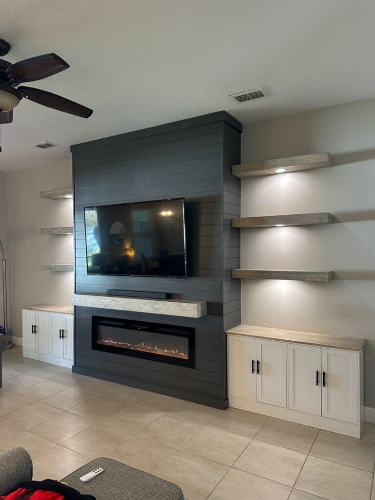 Charcoal shiplap media wall with floating wood shelves and linear fireplace