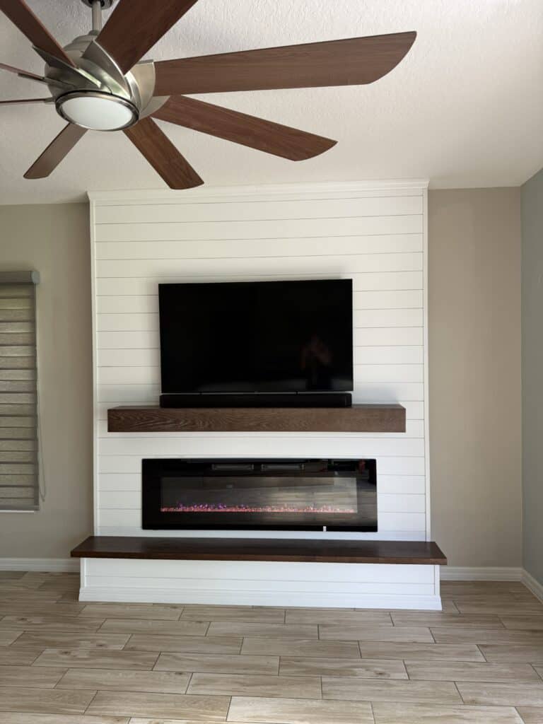 White shiplap media wall with walnut mantel and linear fireplace