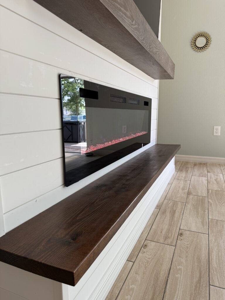 Shiplap fireplace wall detail with stained wood mantel