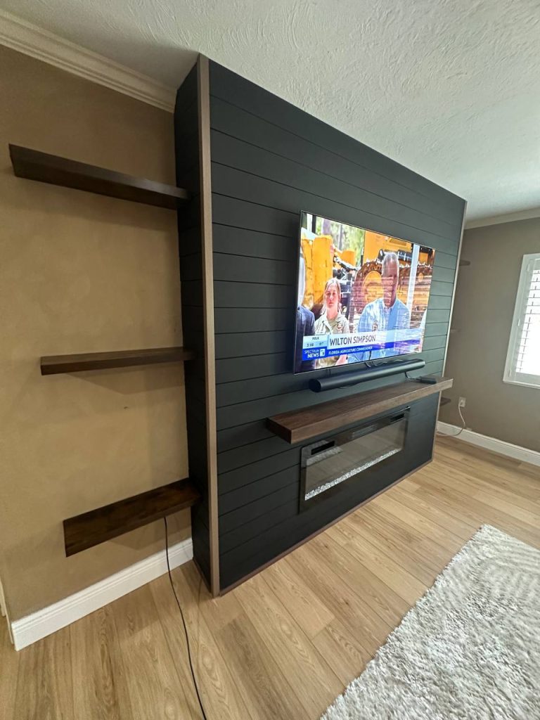 Dark shiplap media wall with electric fireplace and floating shelves