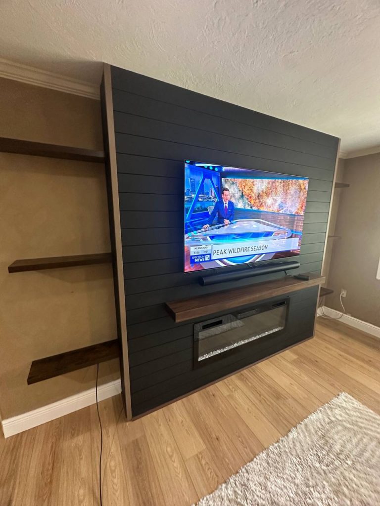 Dark media wall with mounted TV and wood shelves