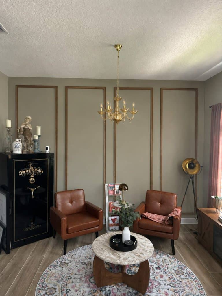Olive green picture-frame molding accent wall with brass chandelier