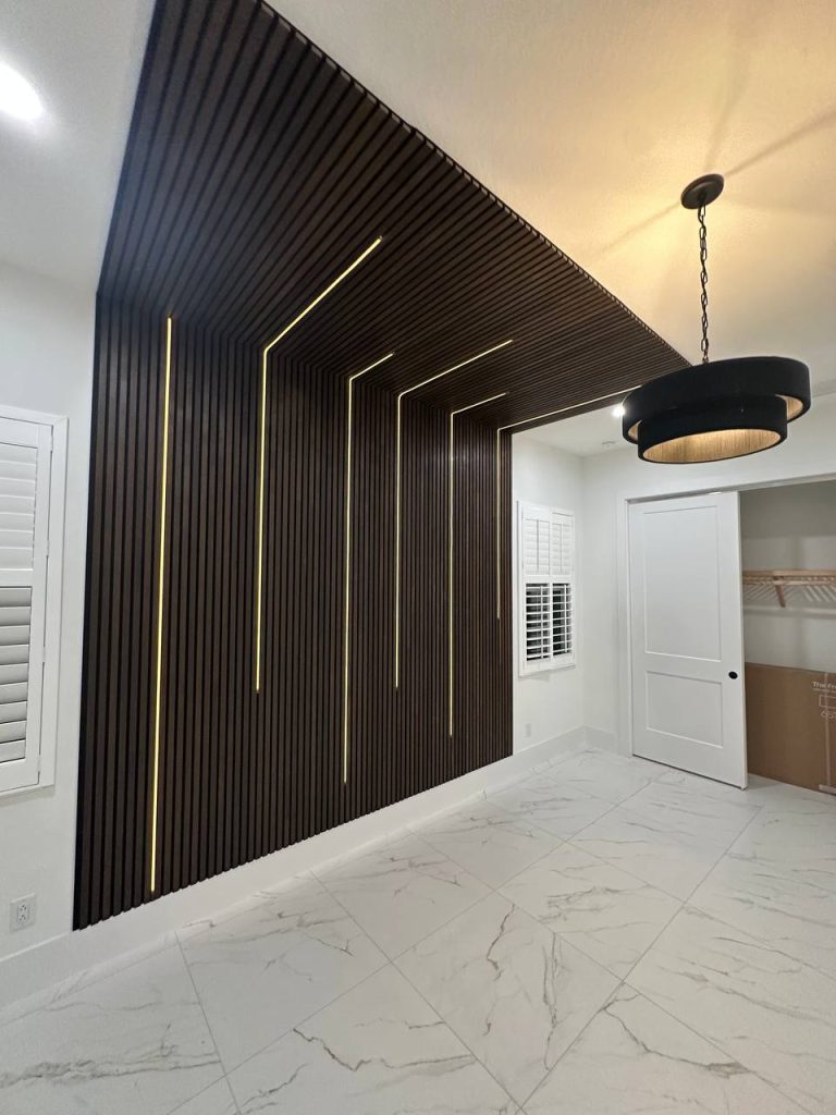 Dark wood slat accent wall with gold LED lines and drum chandelier